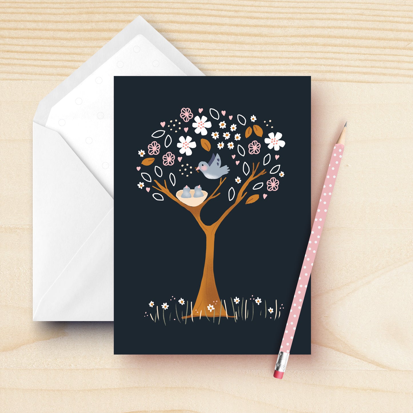 Blank greeting card geaturing a blue bird feeding it's young babies in the nes. The tree is a beautiful pink and white floral tree on a dark blue background. Hand drawn by Kathrin Legg